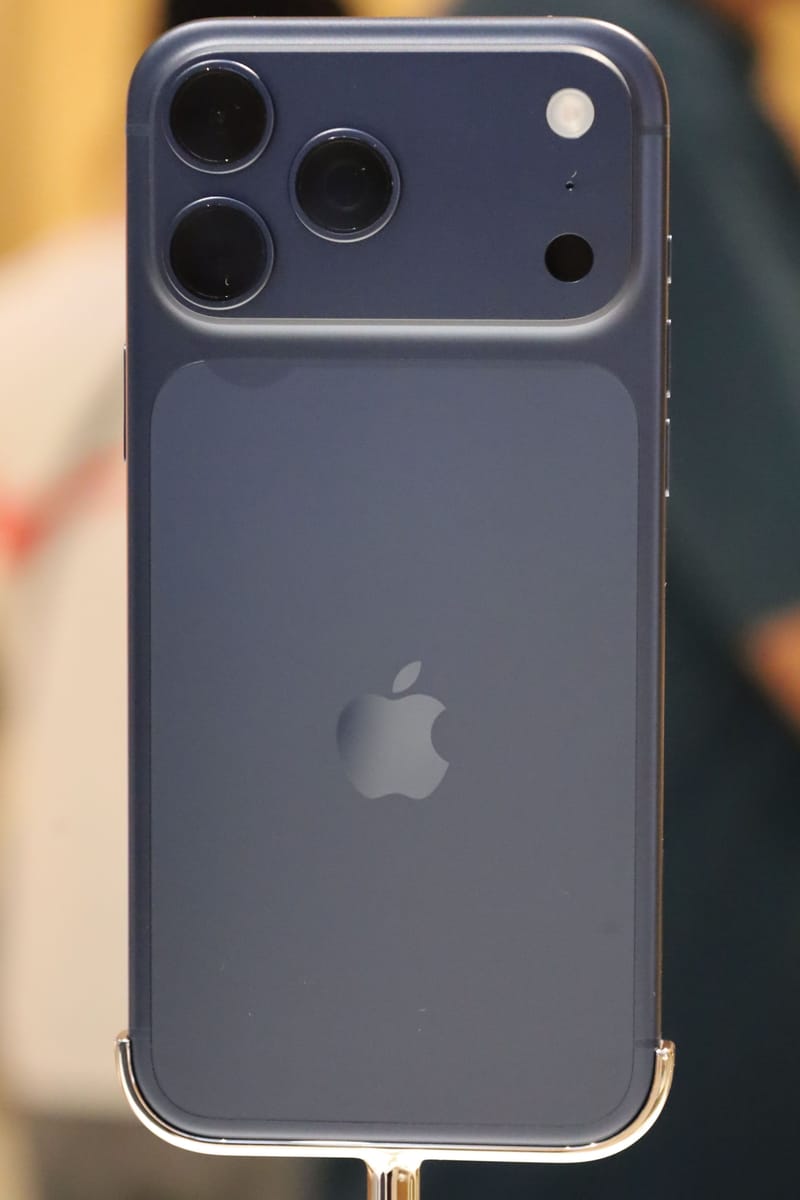 Parte trasera de un iPhone 17 Pro Max en azul intenso sobre un soporte de exposición